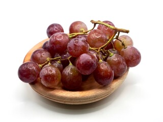 Sweet red grapes on the wooden plate isolated on a white background. Fresh fruit with alot of vitamin C