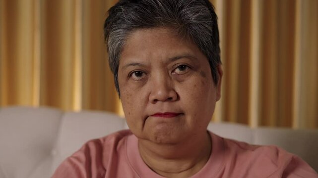 Video footage captured and close up face of Senior short-haired, Asian woman who looking directly at camera with anger