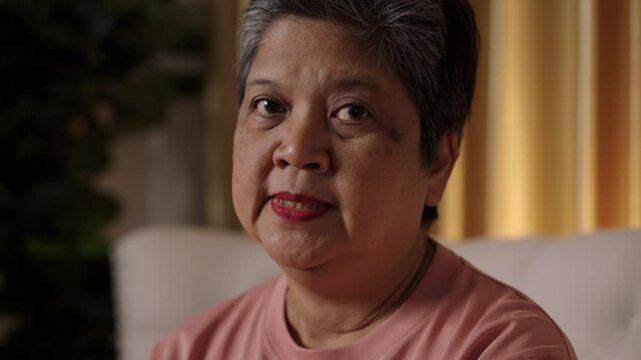 Video footage captured and close up face of Senior short-haired, Asian woman who looking directly at camera talk with anger