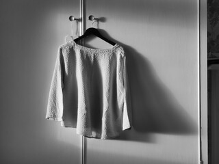 Monochrome image of ladies blouse on hanger with shadows