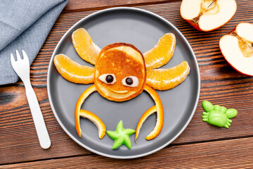 Funny crab face shape snack from pancake, orange,apples. Cute kids childrens baby's sweet dessert, healthy breakfast,lunch, food art on wooden background,top view