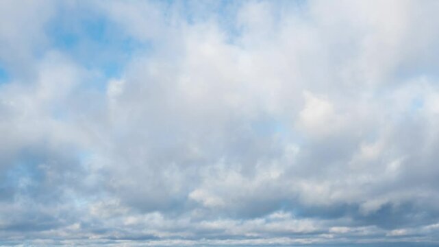 Time lapse of white and dark gray fluffy clouds moving fast in the blue sky on the horizon. Natural background, 4K resolution.