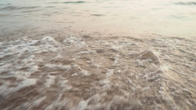 Waves gently lap at shore during stunning sunset over ocean. Golden sunlight reflects off waves as they roll onto shore, creating tranquil atmosphere at sunset by sea. Montenegro summer, Canj