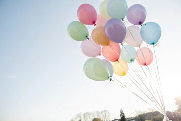 Delicate rainbow colored balloons floating in mid air, feathery look, ethereal, floaty appearance, weightless balloon