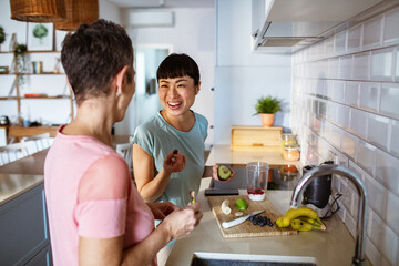 Lesbian couple making healthy organic smoothie together in modern kitchen