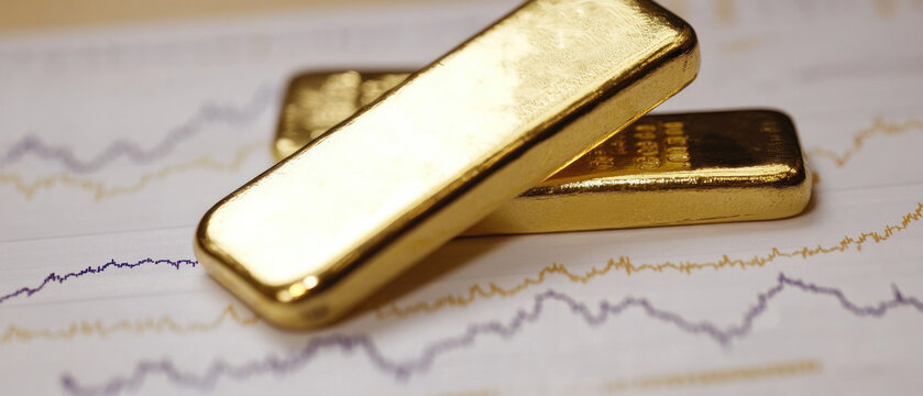 Gold bars on fluctuating financial graph background