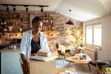 Young woman opening up the package she received in the mail at home in th ekitchen