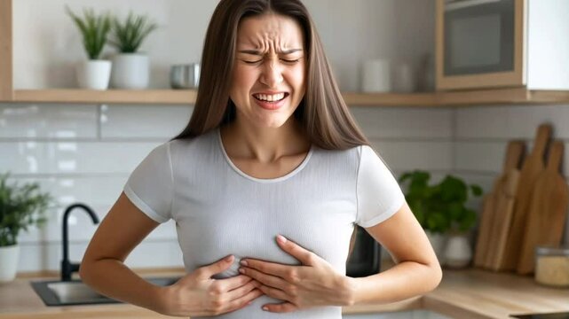 Young woman experiencing chest pain in a modern kitchen, concept of health issues