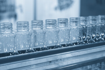 The  empty drinking water bottles  on the conveyor belt for filling process in the light blue scene.