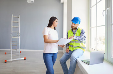 Fototapeta premium Woman and serious young successful professional repairman talking to consider flat plan documents, share maintenance information, planning collaborative building project, choosing paint, designing 