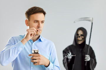 Portrait of a young man wearing shirt smoking cigarette with a male person in Halloween grim reaper...