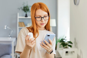 Focused woman holds a bottle of pills and searches for information about medication online using...