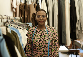 Fototapeta premium Confident young African female fashion designer standing in her studio