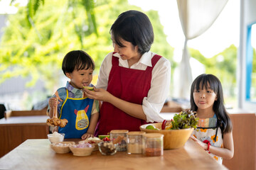 Happy asian family cooking together in the kitchen, tasting food ingredients