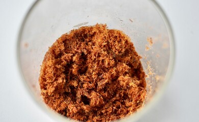 Beef meat floss or abon sapi in glass container isolated on horizontal white background.