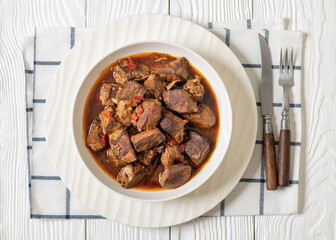beef stew in a white bowl on rustic wooden table