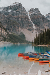 Obraz premium Morning at Moraine Lake with Canoes, Crystal Clear Water, Forests, and Majestic Mountains