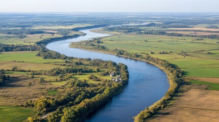 Fototapeta premium Aerial View of Serpentine River Flowing Through Lush Green Fields Under Clear Sky with Gentle Rolling Hills in Scenic Landscape