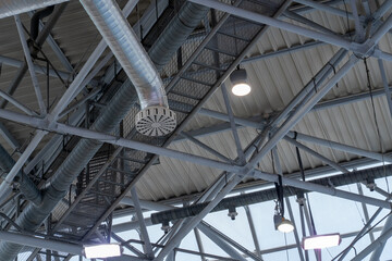 The ceiling features intricate metal beams, ventilation ducts, and lighting fixtures, showcasing a modern indoor architectural design