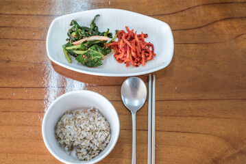 Korean Barley Rice Bowl with Banchan and Traditional Utensils on Wooden Table