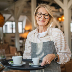 mature woman waitress in apron offer cup of delicious tasty coffee