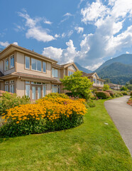 Obraz premium Neighbourhood of luxury houses in summer with street road, big trees and nice landscape in Vancouver, Canada. Blue sky. Day time on August 2024.