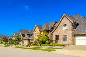Neighbourhood of luxury houses in summer with street road, big trees and nice landscape in Vancouver, Canada. Blue sky. Day time on August 2024.