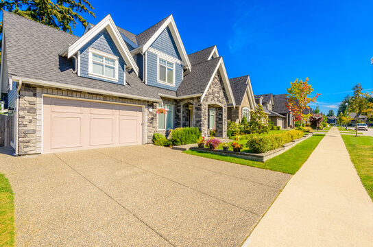 Neighbourhood of luxury houses in summer with street road, big trees and nice landscape in Vancouver, Canada. Blue sky. Day time on August 2024.