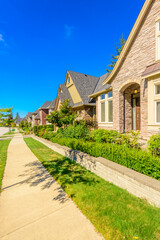 Neighbourhood of luxury houses in summer with street road, big trees and nice landscape in Vancouver, Canada. Blue sky. Day time on August 2024.