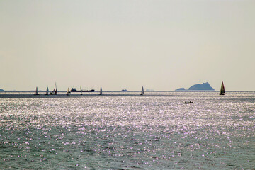view of island and optimist sailboats on the sea 