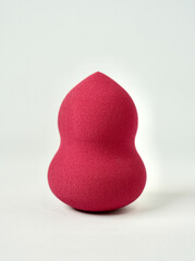 One pink red make up tool soft beauty blender sponge isolated on vertical white background.