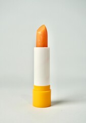 Tinted orange lip balm cosmetic care product isolated on vertical white background.