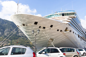 Naklejka premium A large cruise liner docked at the pier against the backdrop of a mountain landscape. Aesthetics of scale.