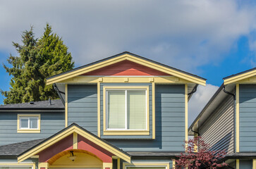 Top of grey stucco luxury house with shingle roof, red and yellow trees and nice windows in Summer in Vancouver, Canada, North America. Day time on June 2024.
