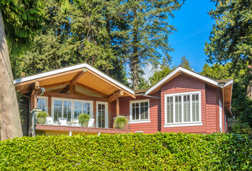 Top of grey stucco luxury house with shingle roof, red and yellow trees and nice windows in Summer in Vancouver, Canada, North America. Day time on June 2024.