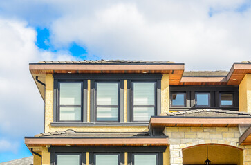 Top of grey stucco luxury house with shingle roof, red and yellow trees and nice windows in Summer in Vancouver, Canada, North America. Day time on June 2024.
