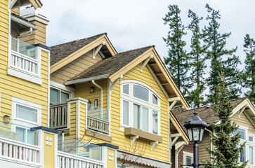 Top of grey stucco luxury house with shingle roof, red and yellow trees and nice windows in Summer in Vancouver, Canada, North America. Day time on June 2024.