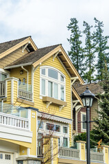 Top of grey stucco luxury house with shingle roof, red and yellow trees and nice windows in Summer in Vancouver, Canada, North America. Day time on June 2024.