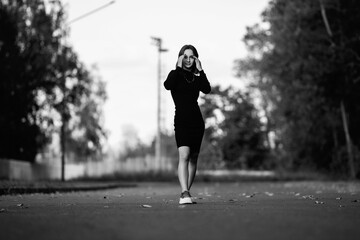 Portrait of a young beautiful dark-haired girl in the park. Black and white photo.