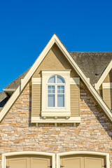 Top of grey stucco luxury house with shingle roof, red and yellow trees and nice windows in Summer in Vancouver, Canada, North America. Day time on June 2024.