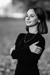 Portrait of a young beautiful dark-haired girl in the park. Black and white photo.