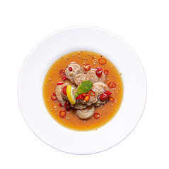 A vibrant dish featuring seafood in a flavorful broth, garnished with chili, herbs, and citrus.