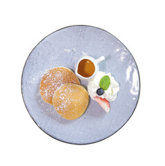 Fluffy pancakes served with whipped cream, fresh fruit, and syrup on a decorative plate.