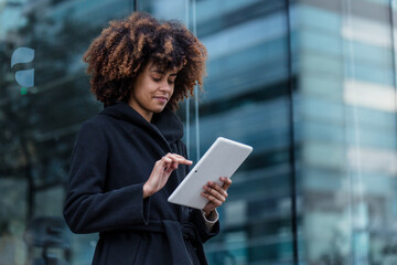 young African American business woman using digital tablet in city of Spain Europe, financial and caribbean people with skyscraper background © Marcos