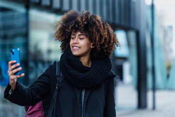 young African American business woman talking and using mobile phone in city of Spain Europe, financial and caribbean people with skyscraper background	