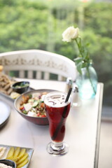 A vibrant red hibiscus iced drink served in an elegant tall glass, showcasing refreshing herbal flavors with a touch of sweetness.