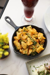 A skillet of crispy batata harra (spicy Lebanese potatoes) sautéed with garlic and garnished with fresh parsley, offering a flavorful and authentic Middle Eastern side dish.