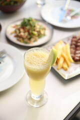 Refreshing green apple smoothie in a tall glass garnished with apple slices, served on a marble table in a serene outdoor setting.