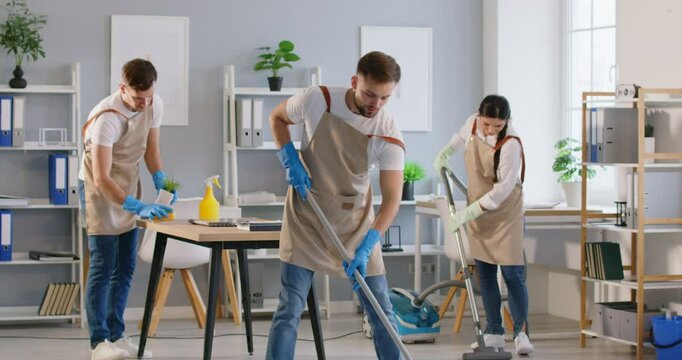 Group of smiling cleaners from cleaning service is joyfully dancing while efficiently cleaning the office. The staff is actively engaged in chores, ensuring a sparkling clean workspace.