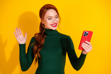 Photo of charming positive woman wear green turtleneck waving hi talking modern gadget empty space isolated yellow color background © deagreez